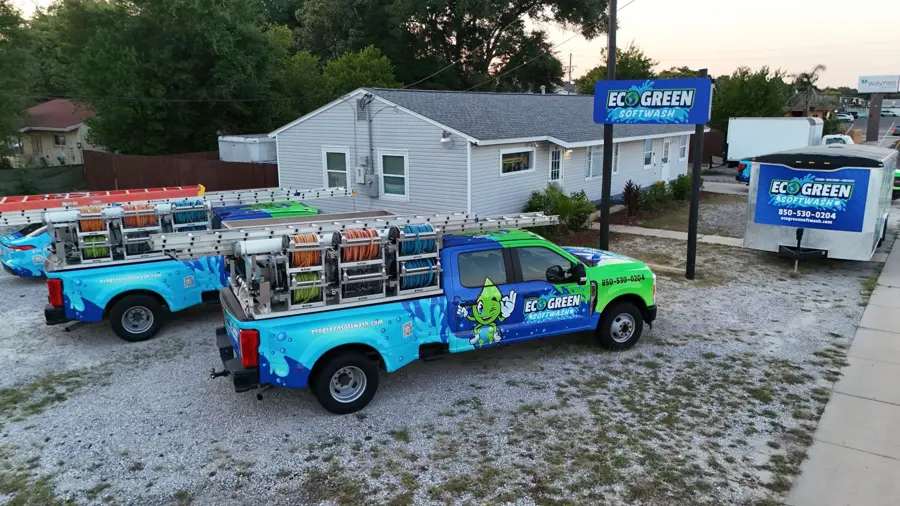 Branded Eco Green Softwash trucks beside the shop sign